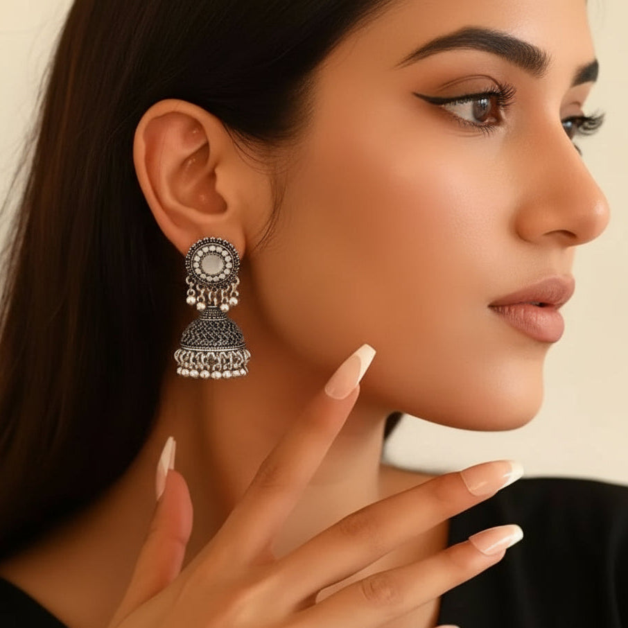 Close-up of a woman wearing an ornate silver earring with a neutral background