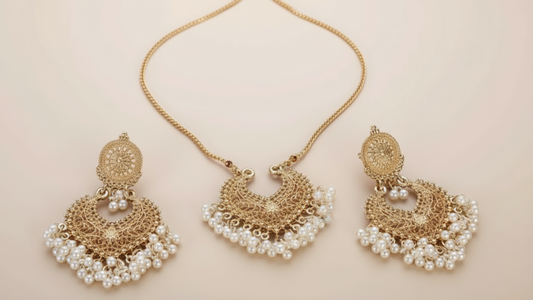 Gold and pearl necklace with matching earrings on a white background